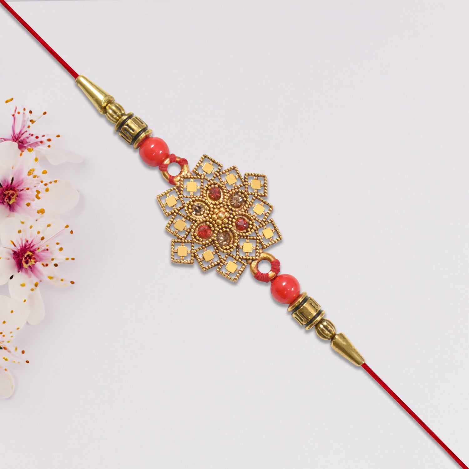 Traditional Golden Floral Rakhi With Intricate Design And Red Beads On Red Thread Traditional Golden Floral Rakhi With Intricate Design And Red Beads On Red Thread